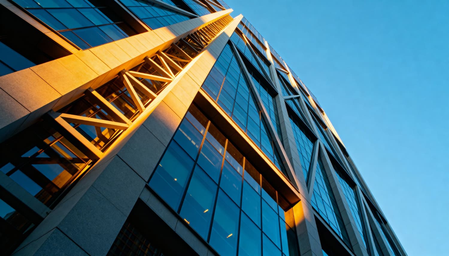 Modern glass building viewed from below against a blue sky